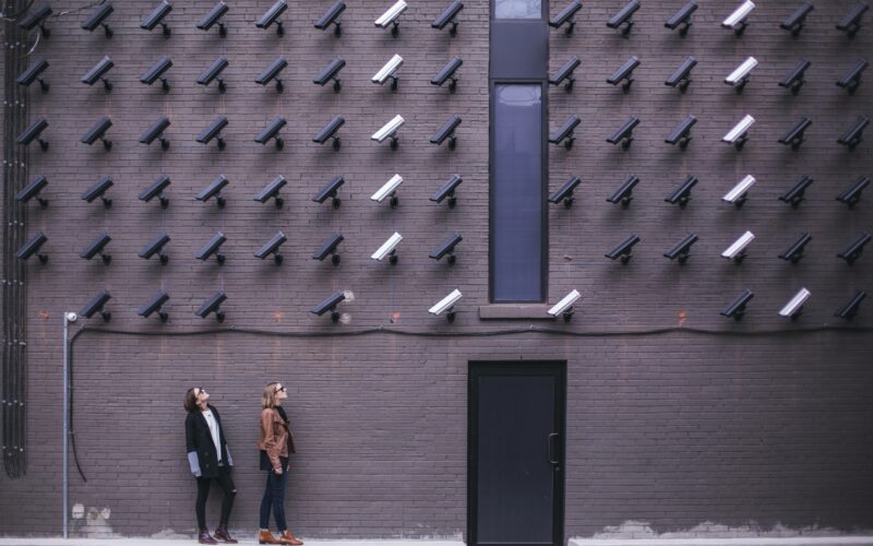 two women facing security camera above mounted on structure